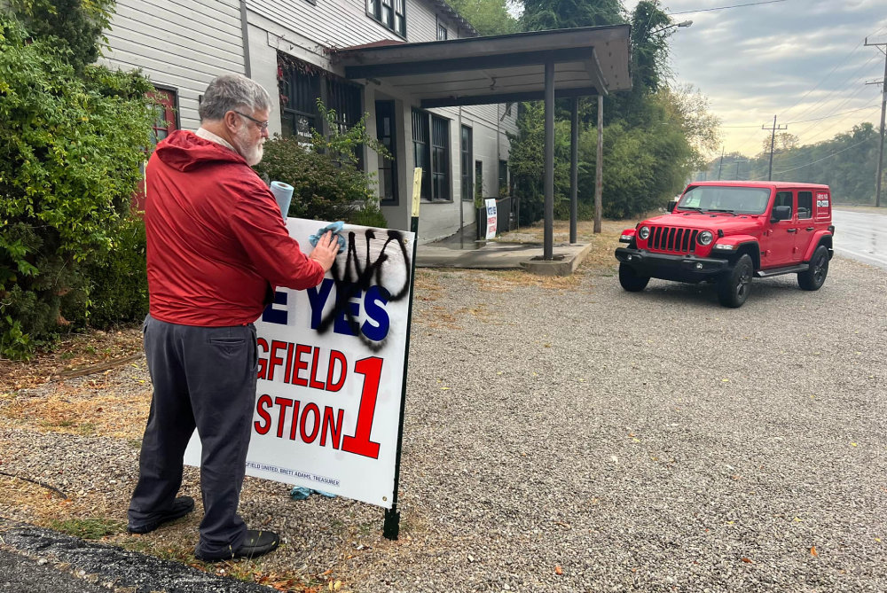 Ron Boles of the Galloway Village Neighborhood Association cleans up a defaced campaign sign belonging to his organization’s opponent on Question 1, Springfield United. 